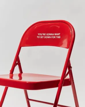 Red folding chair reading you're gonna want to sit down for this