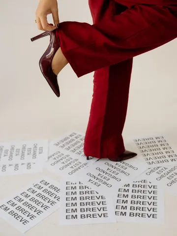 Red heels and red trousers over printed papers